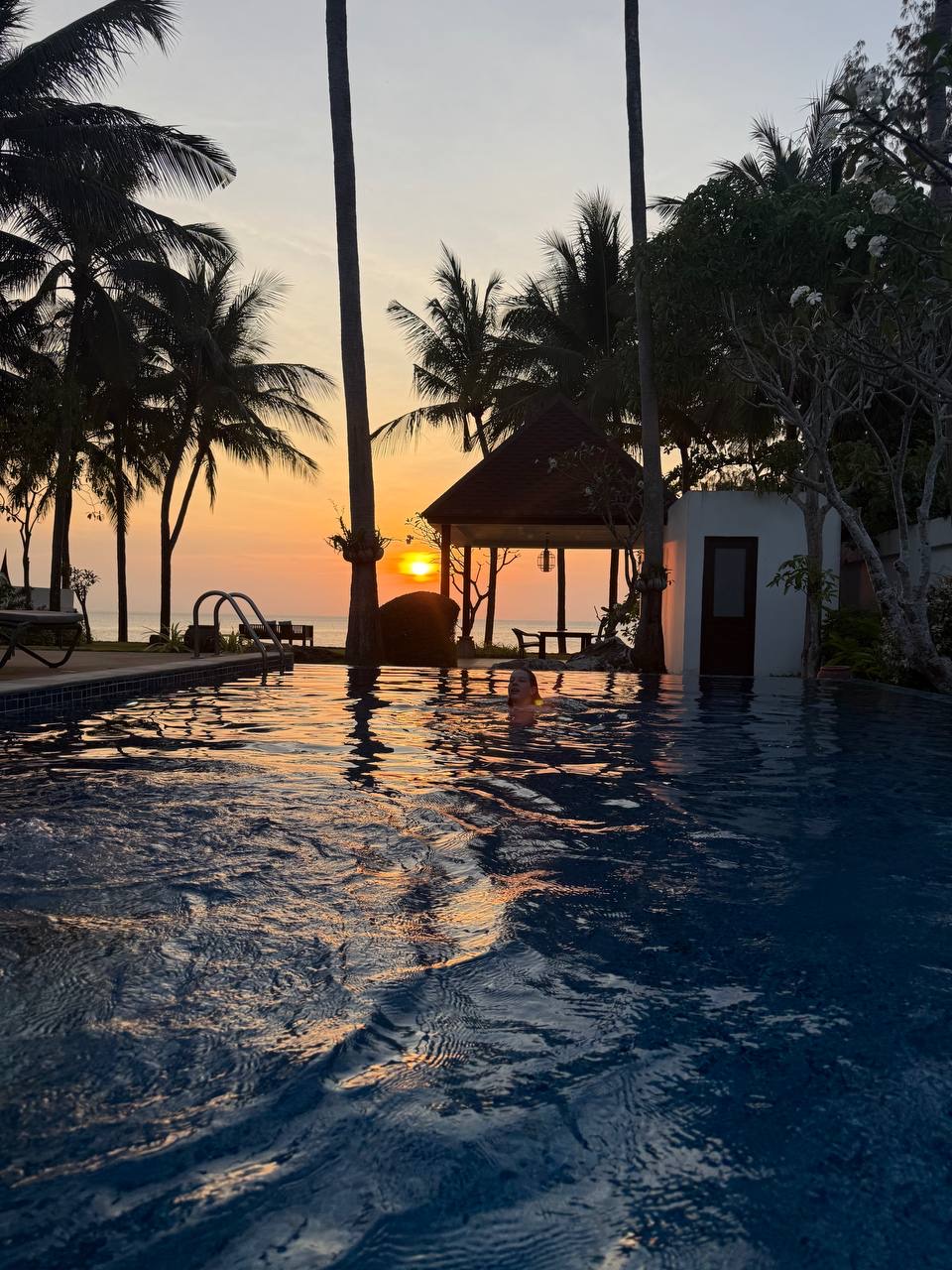 Sunset view over an infinity pool with palm trees