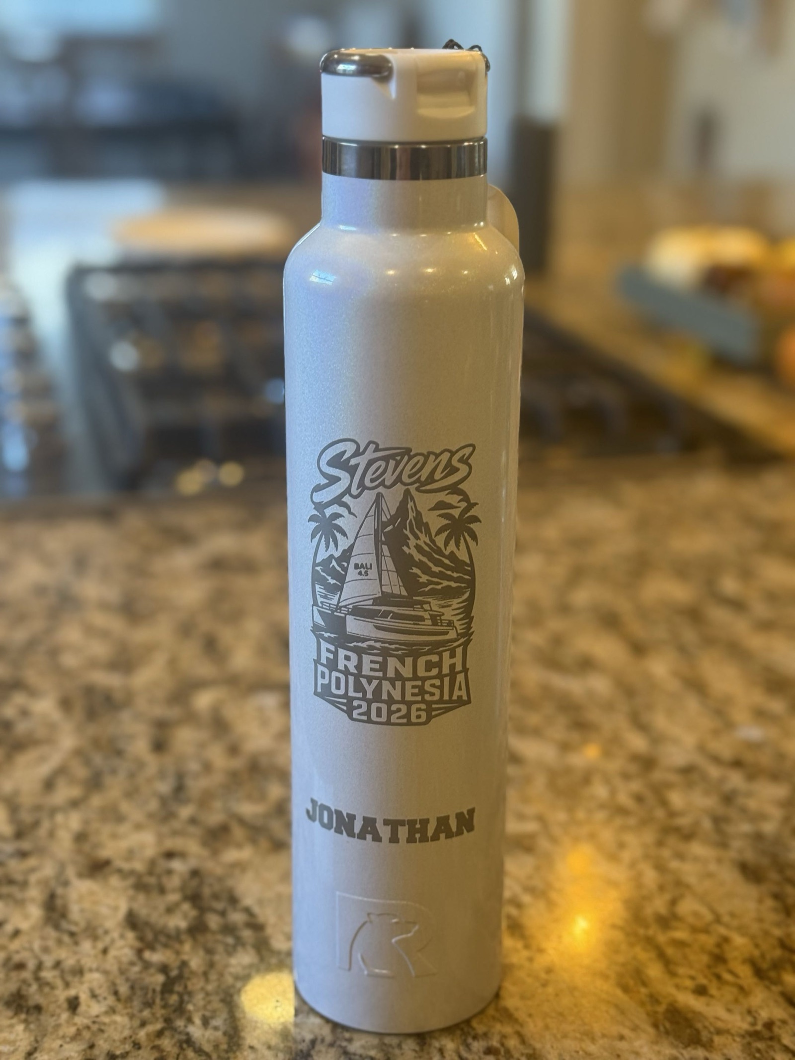 A white RTIC water bottle engraved with Stevens, a Bali 4.5 catamaran under sail in front of a mountain and palm trees, French Polynesia 2026, and the name Jonathan